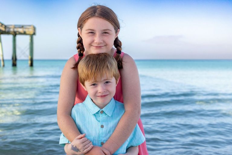 Beach portraits captured at sunset with turquoise ocean waves and pier in background