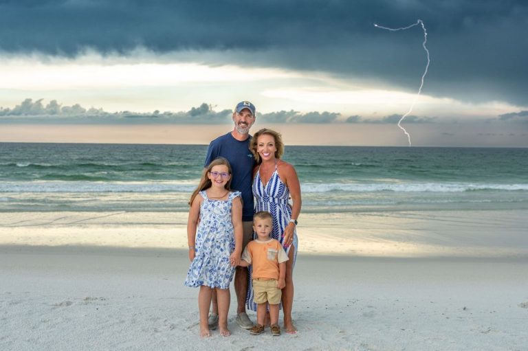 Family enjoying a sunset photoshoot on a scenic beach with dramatic cloudy sky