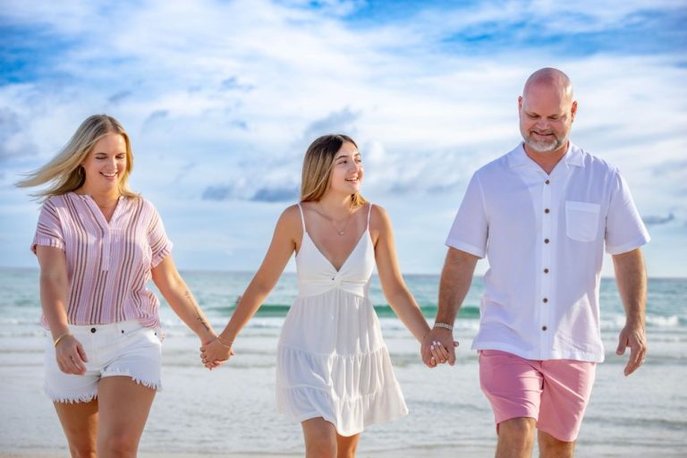 Family walking together on beach wearing coordinated white and pink outfits